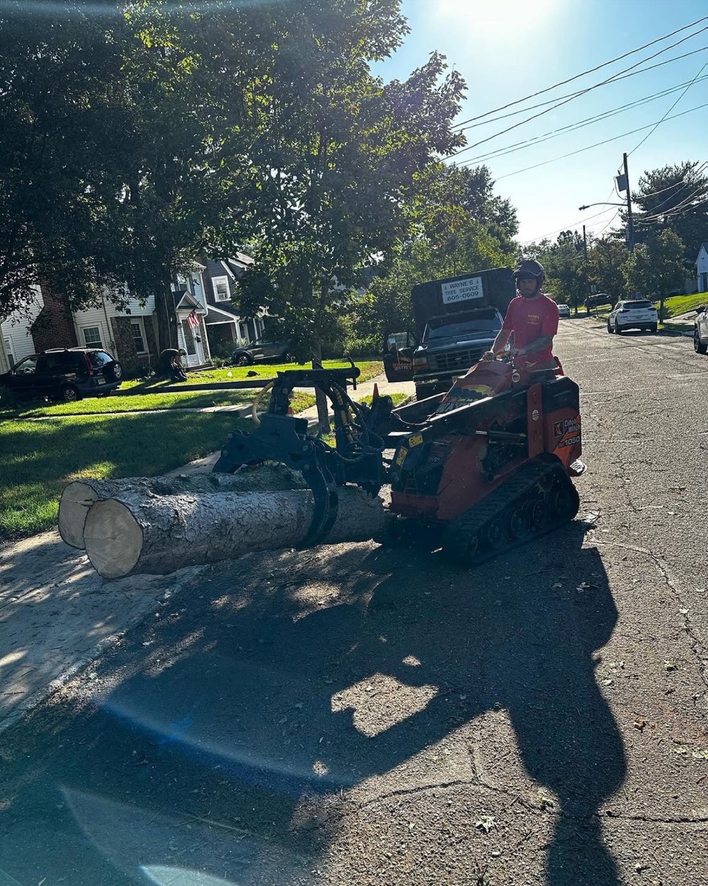 Tracked loader carrying a cut log along a street